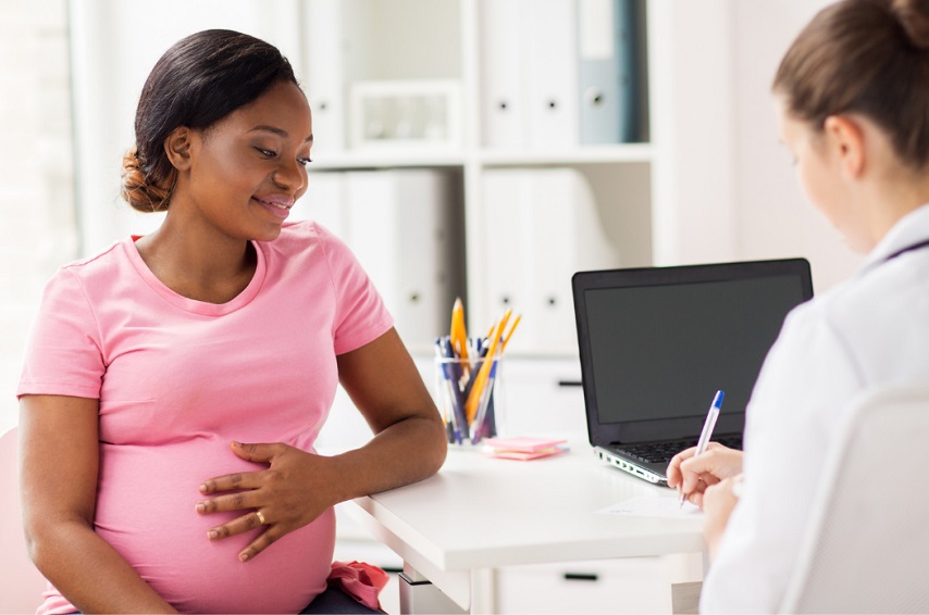Médica obstetra atende gestante sorridente durante consulta pré-natal