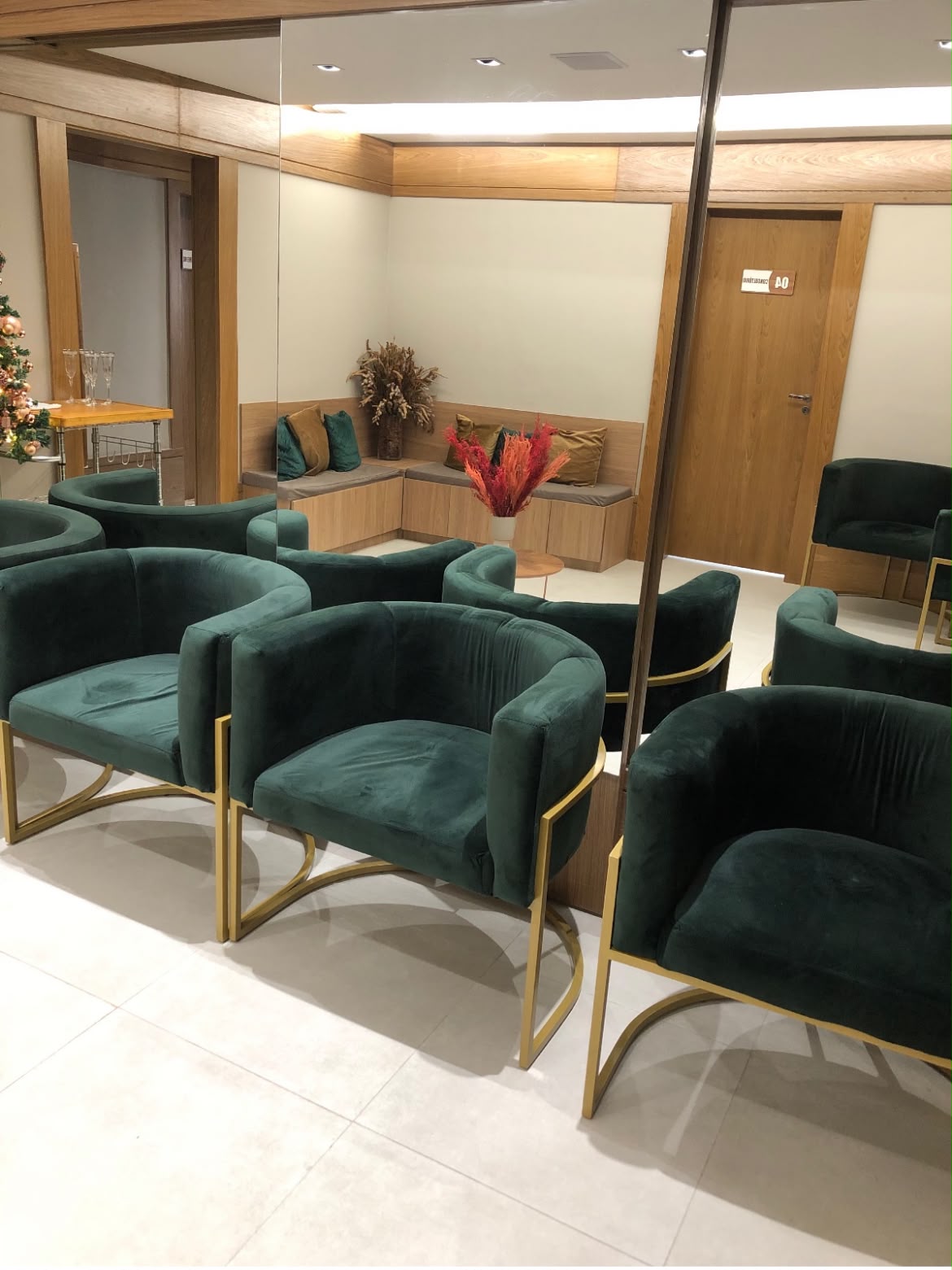 Sala de espera com poltronas verdes e detalhes dourados
