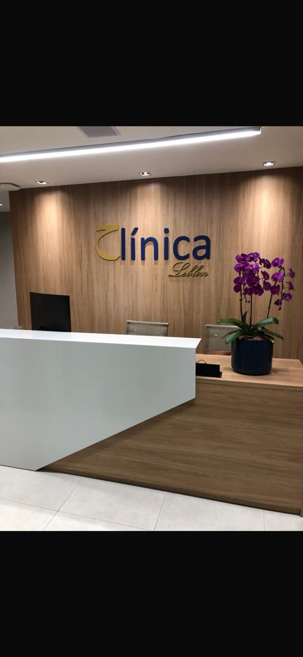 Recepção da Clínica Leblon com painel de madeira e orquídeas